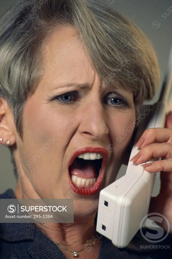 Close-up of a mid adult woman shouting on a cordless phone