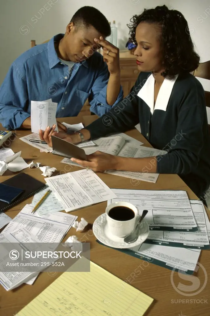 Young woman sorting out bills with a young man sitting near her