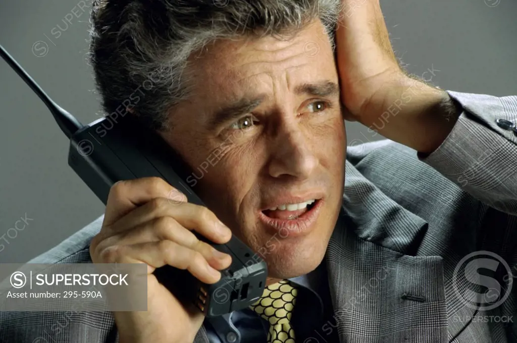 Close-up of a businessman using a cordless phone and looking stressed