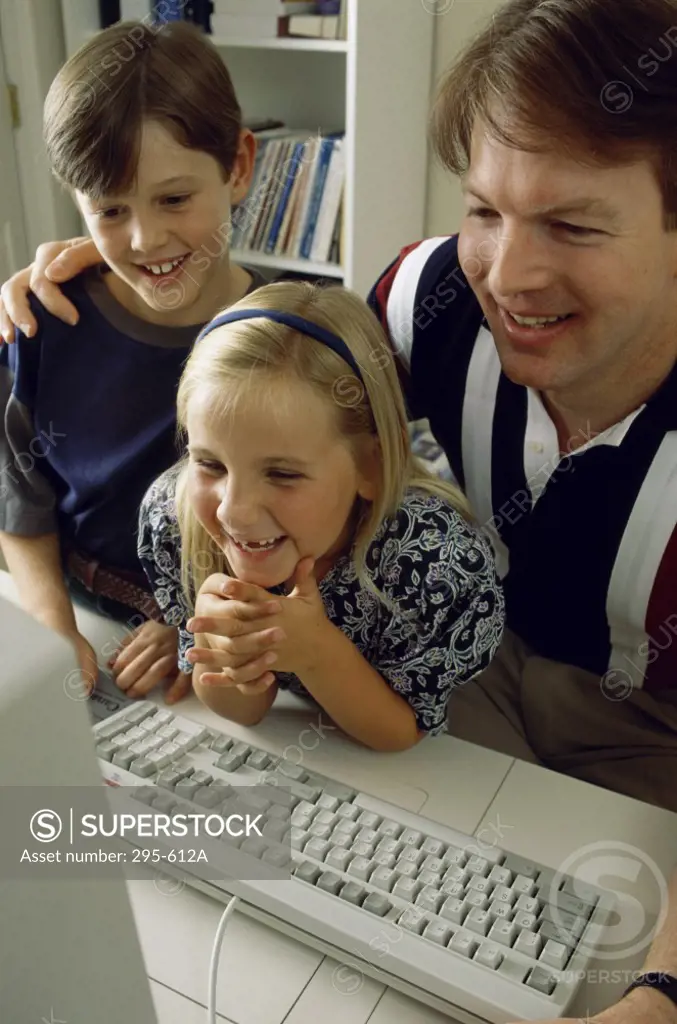 Mid adult man with his son and daughter sitting in front of a computer