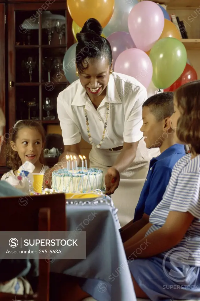 Mid adult woman serving cake to children at a birthday party