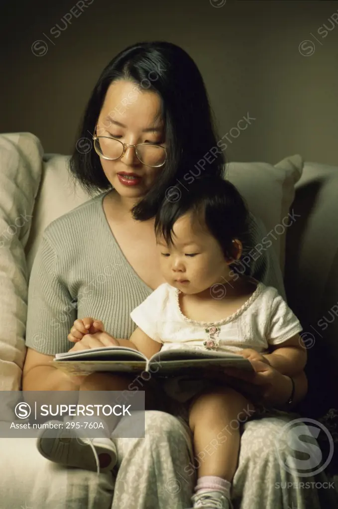 Young woman reading a book to her daughter