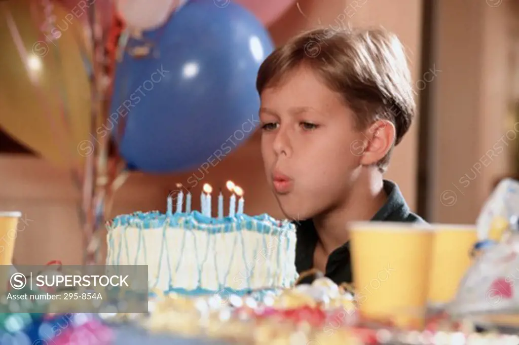 Close-up of a boy blowing out candles on a birthday cake