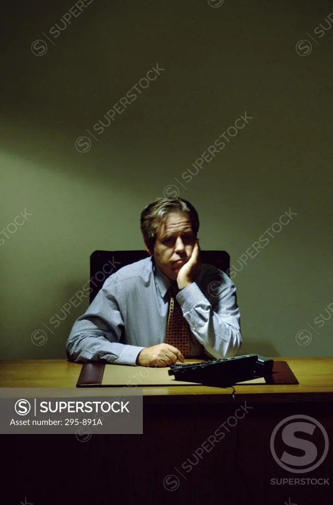 Businessman sitting at a desk with his hand on his chin