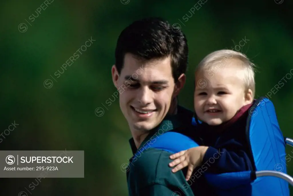 Close-up of a young man carrying his son in a baby carrier