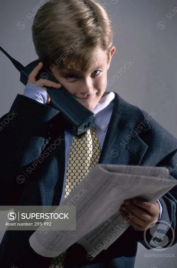Boy dressed as a businessman using a cordless phone
