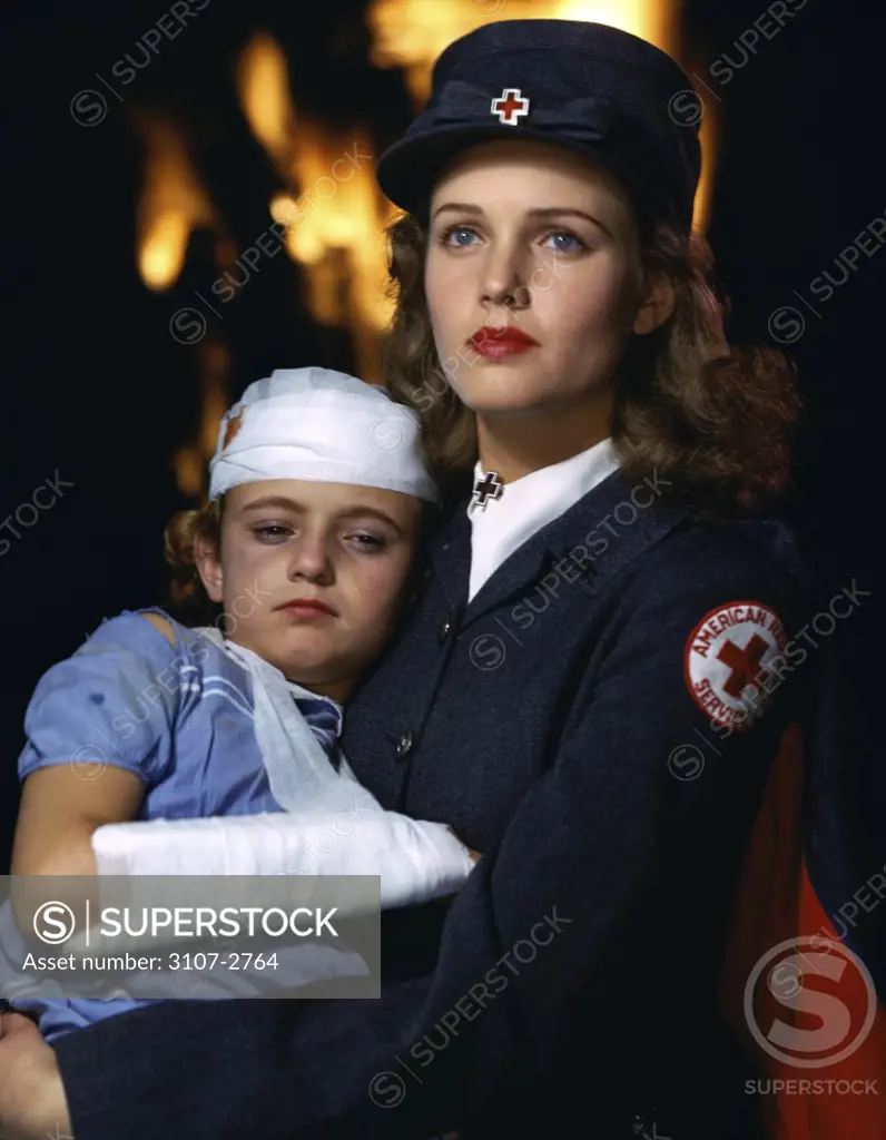 Side profile of a red cross woman carrying an injured girl