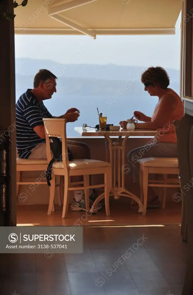 Couple eating food in restaurant, Oia, Santorini, Cyclades Islands, Greece
