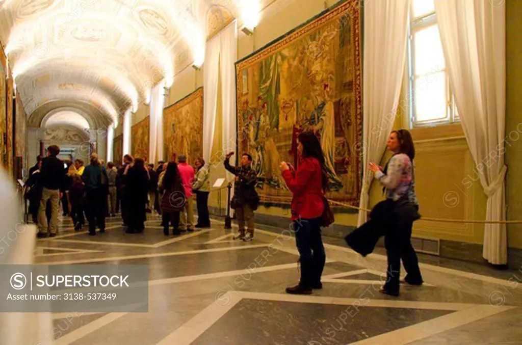 Tourists contemplate and photograph art works in the Gallery of Tapestries, Vatican Museums, Vatican City