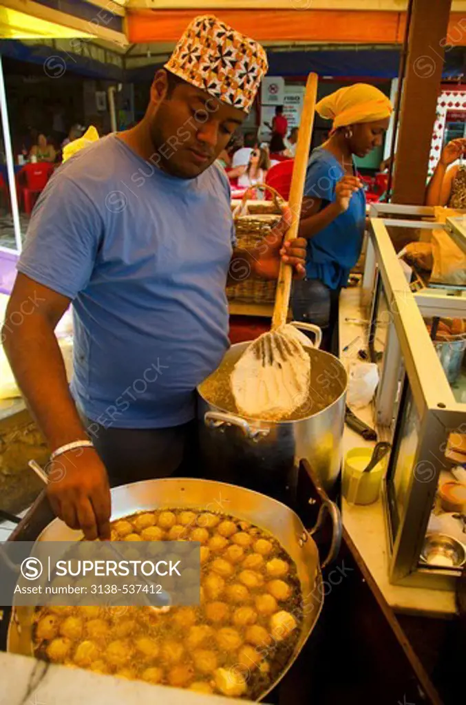 Man preparing traditional bean paste dumplings called acaraje, Salvador, Bahia, Brazil