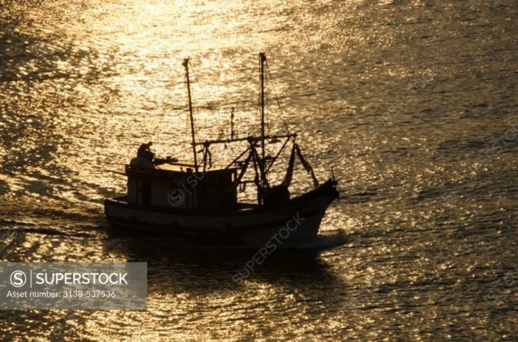 Silhouette of a fishing boat in the bay at sunset, Paraty, Rio De Janeiro, Brazil