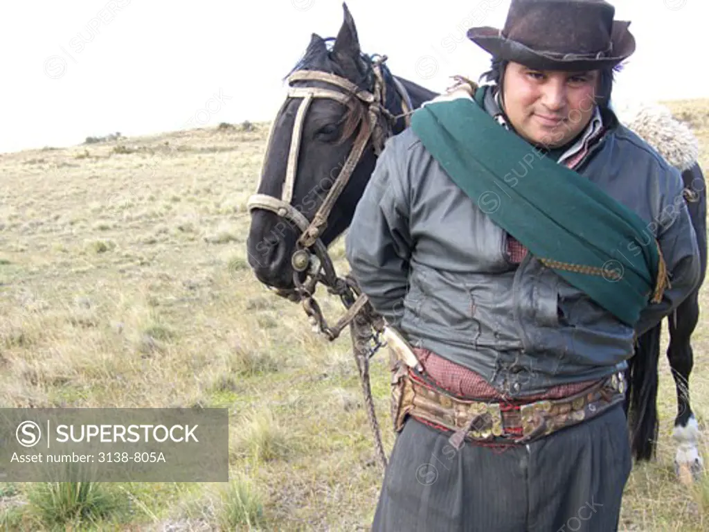 Gaucho standing in a field with his horse, Patagonia, Argentina