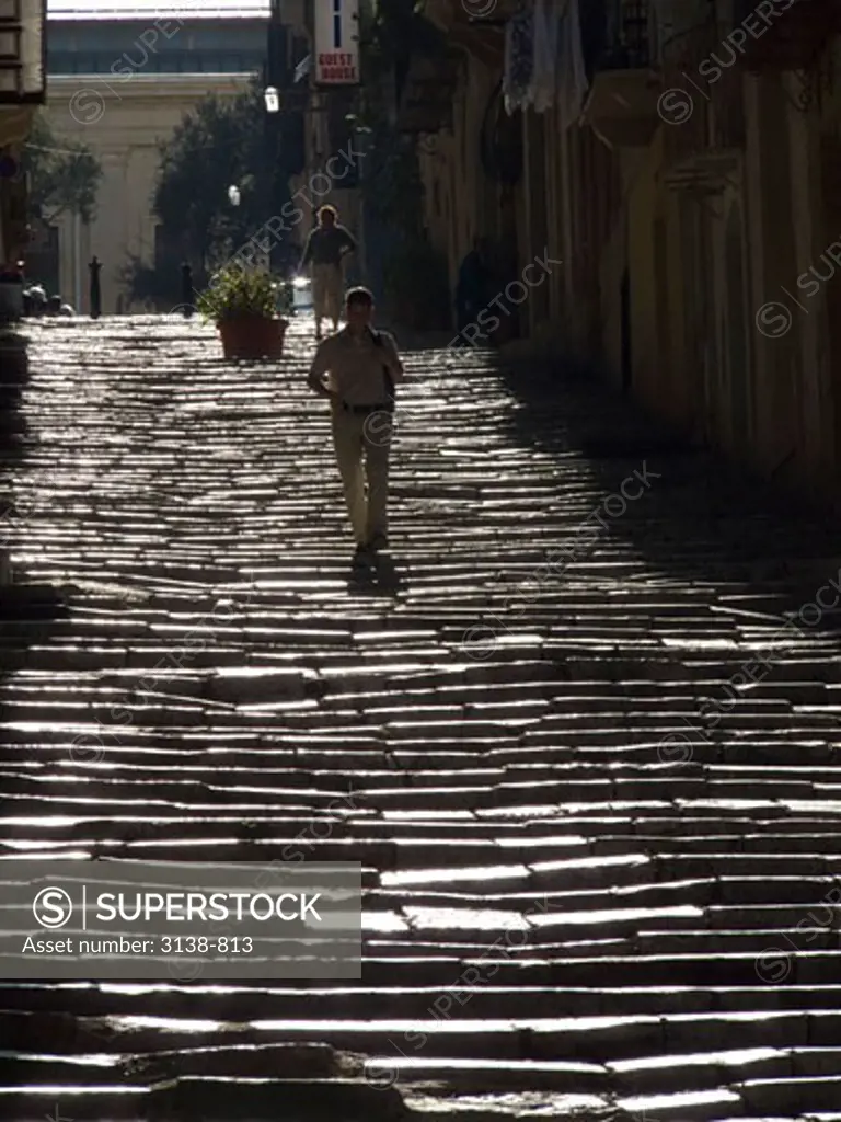 Two men walking down staircase, Malta