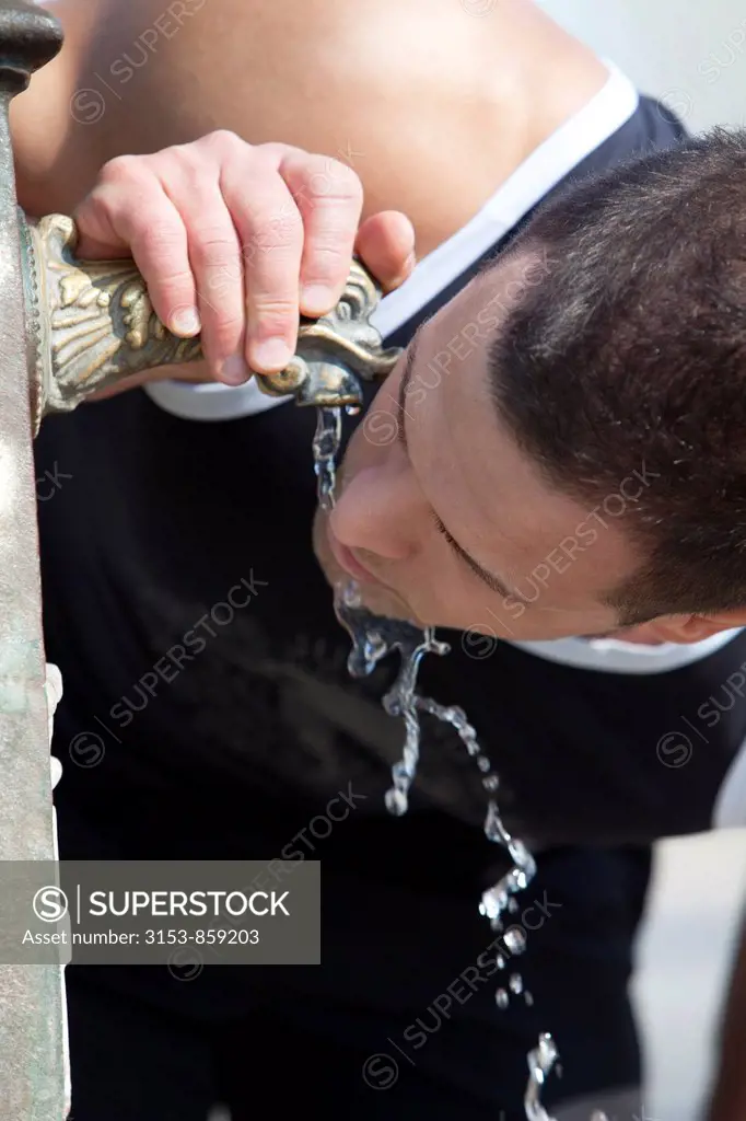 man drinking from a fountain