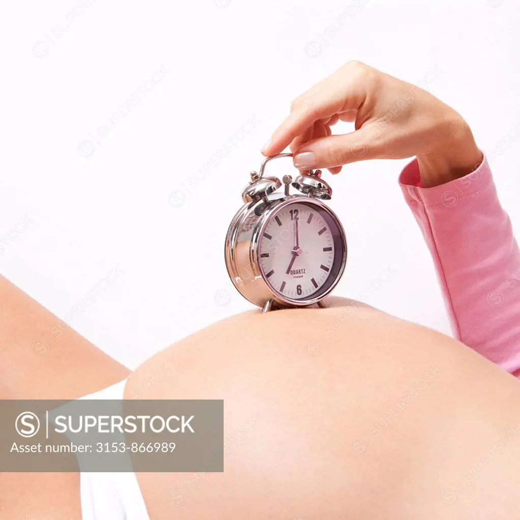 pregnant woman with alarm clock on the belly
