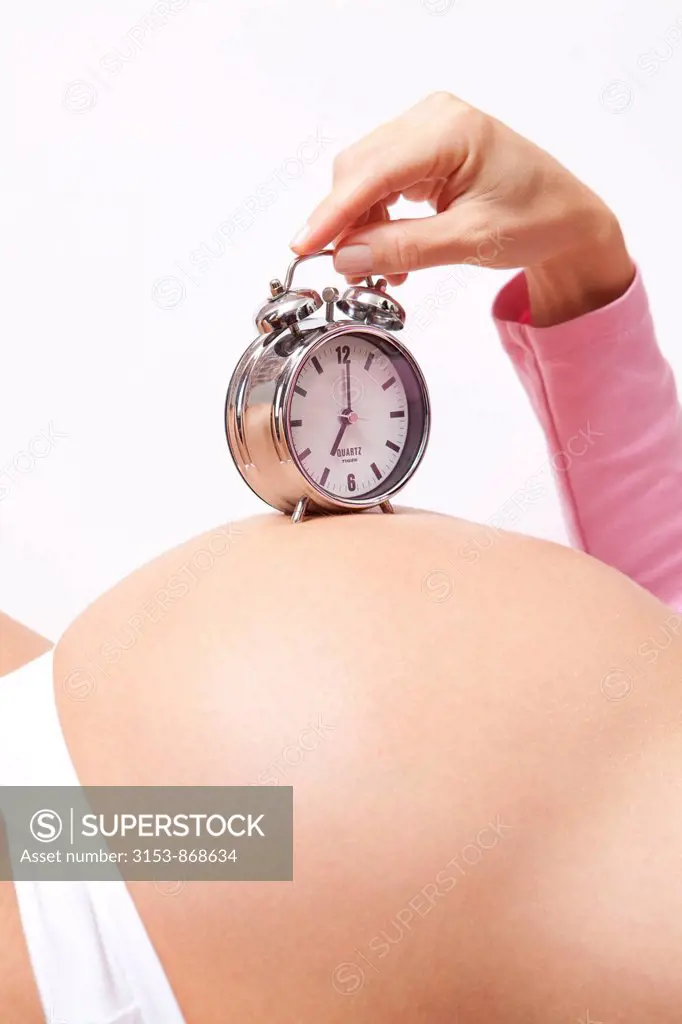 pregnant woman with alarm clock on the belly