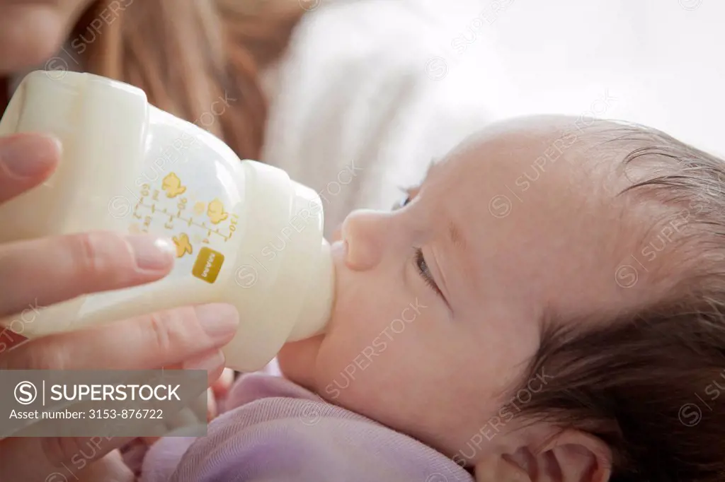 newborn baby girl nursed with baby bottle