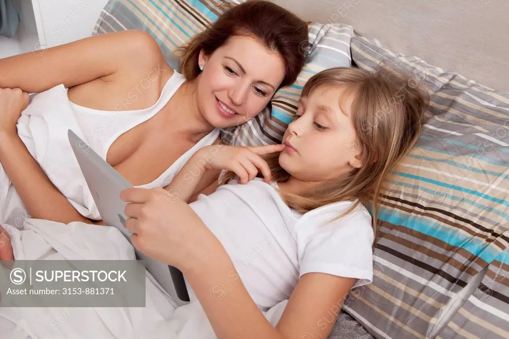 mother and daughter on the bed with ipad