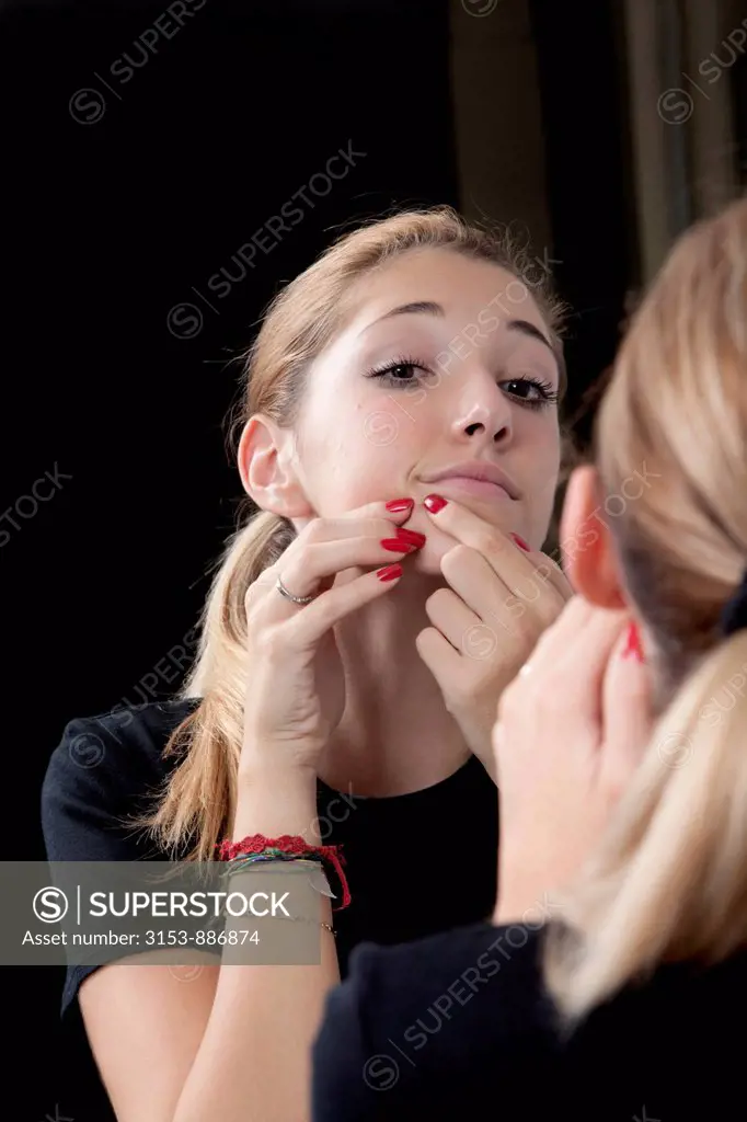 teenage girl squeezing a pimple