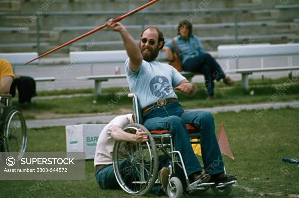 Man sitting in a wheelchair throwing javelin