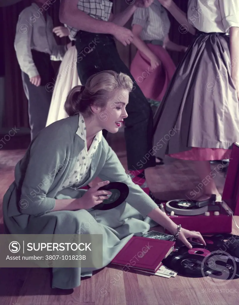 Side profile of a teenage girl sitting on the floor and selecting musical records