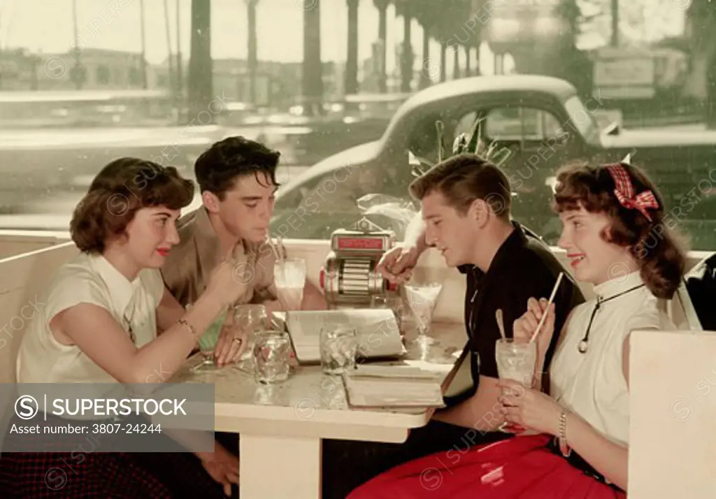 Side profile of two young couples drinking milkshakes at a restaurant