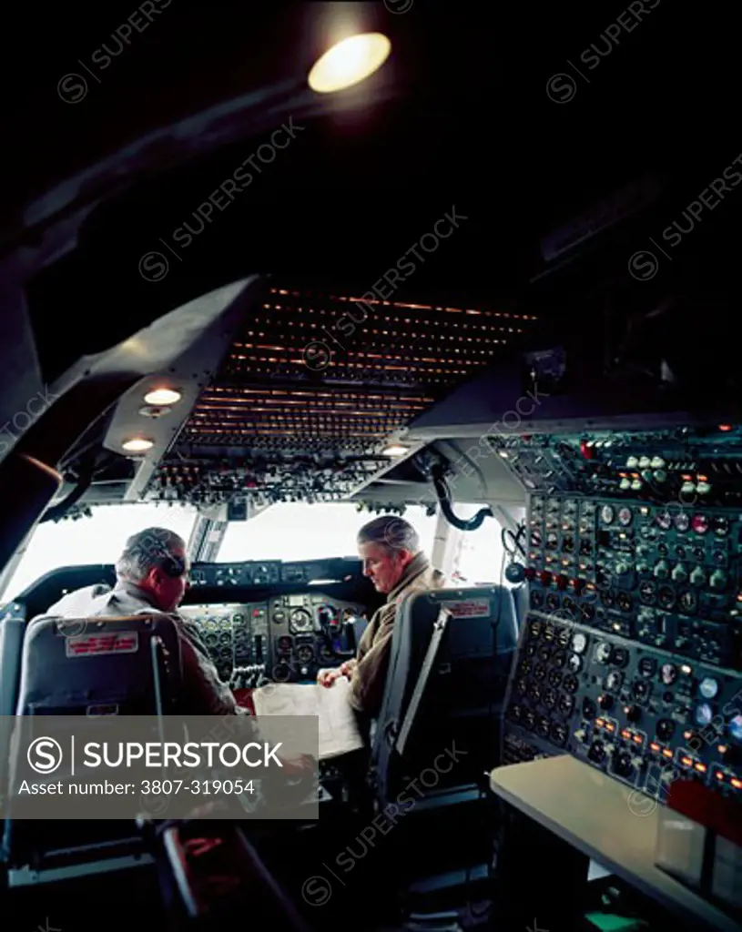 Rear view of two pilots in the cockpit of an airplane
