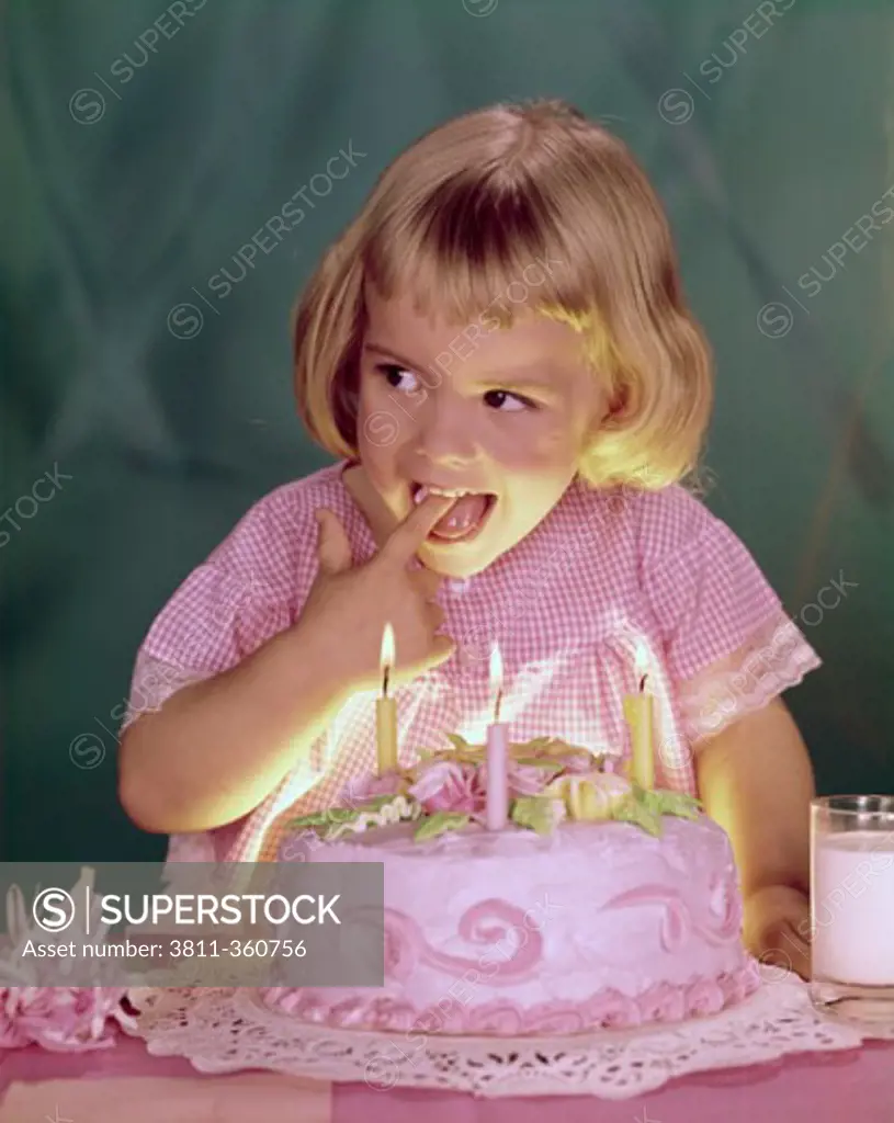 Close-up of a girl licking the icing of a birthday cake