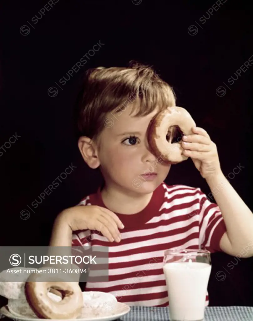 Close-up of a boy looking through a donut