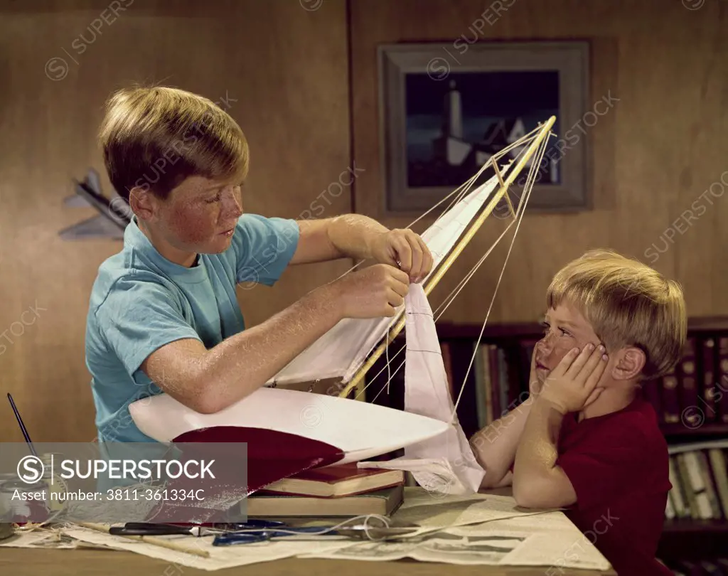 Two boys assembling a model of sailboat
