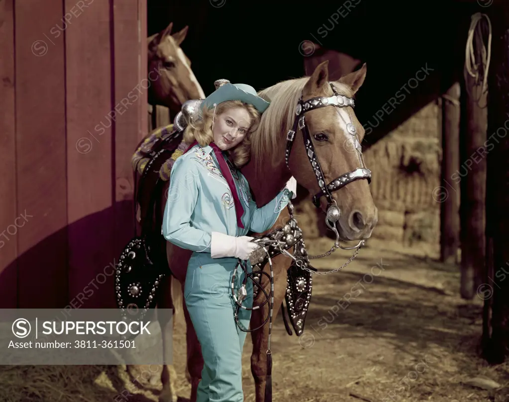 Portrait of a young woman standing near a horse