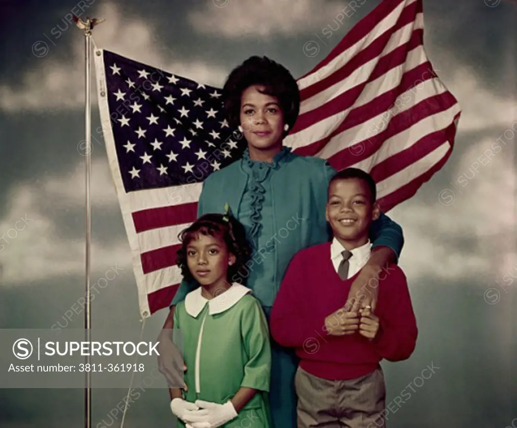 Portrait of a mid adult woman standing with her daughter and son in front of an American flag