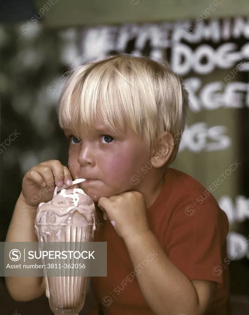 Close-up of a boy drinking milkshake and thinking