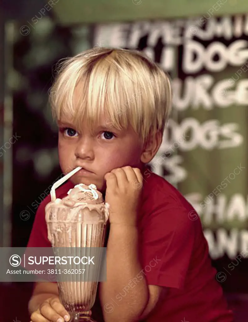 Close-up of a boy drinking an ice cream float with a drinking straw