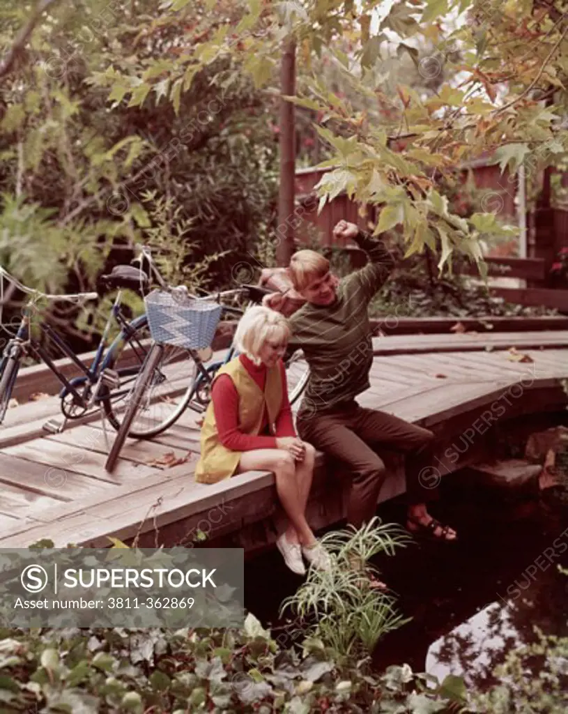 High angle view of a teenage couple sitting on a wooden bridge