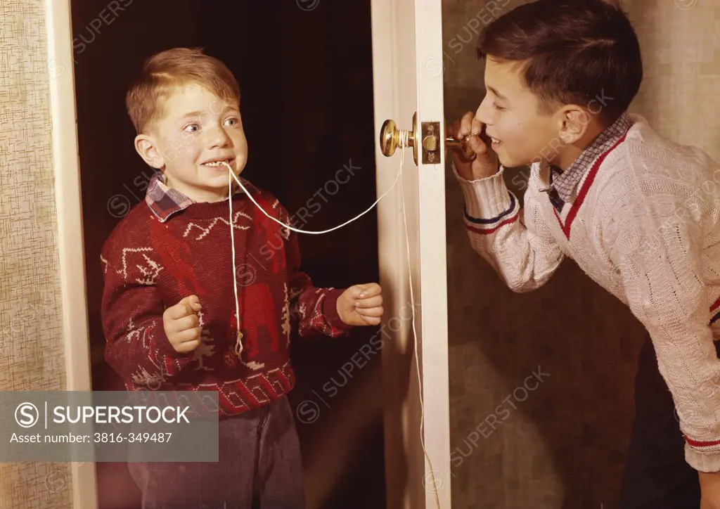 Boy attempting to extract his brother's loose tooth using string and doorknob technique