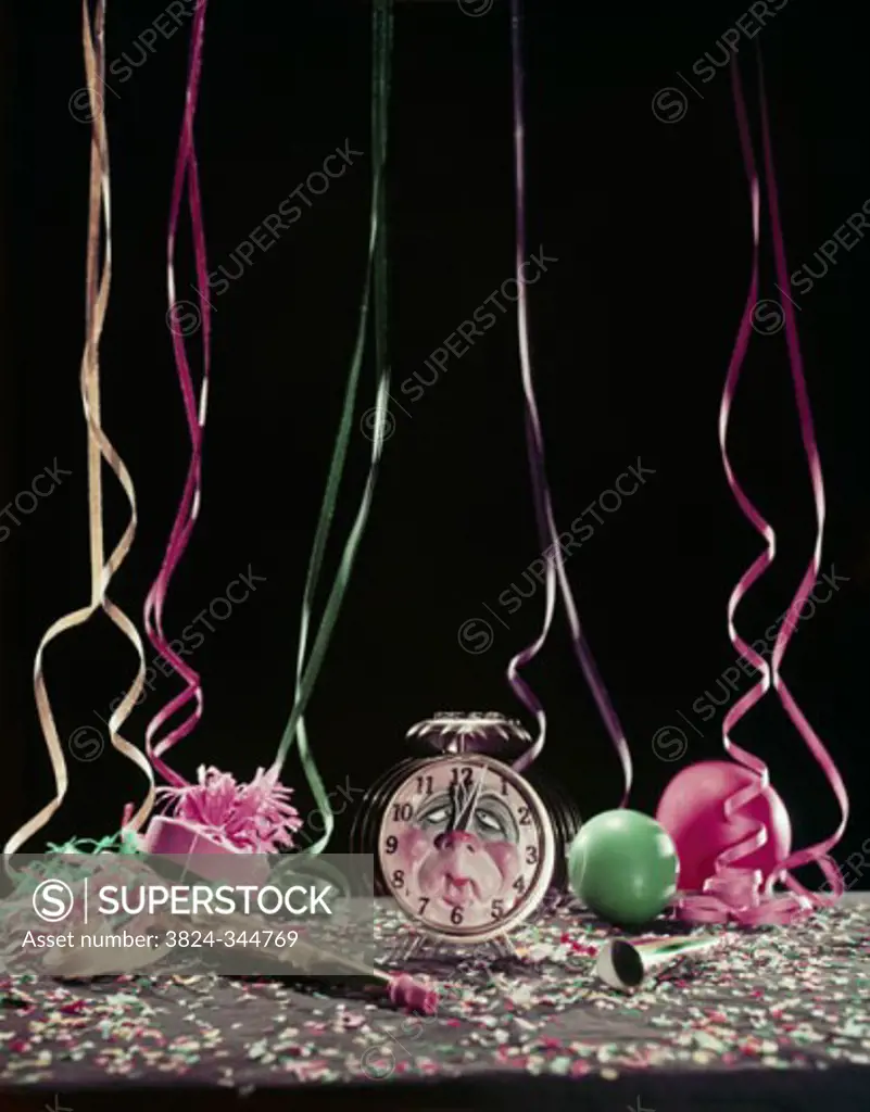 Studio shot of alarm clock with party horn blowers and confetti
