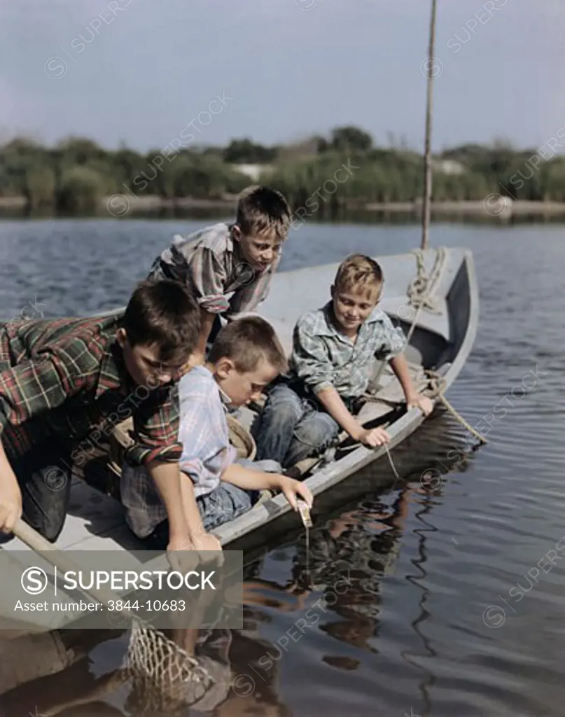 Four boys sitting in a boat and fishing