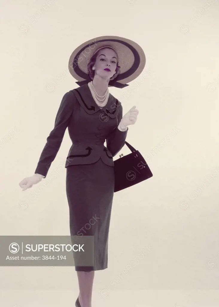 Studio portrait of young elegant woman carrying purse