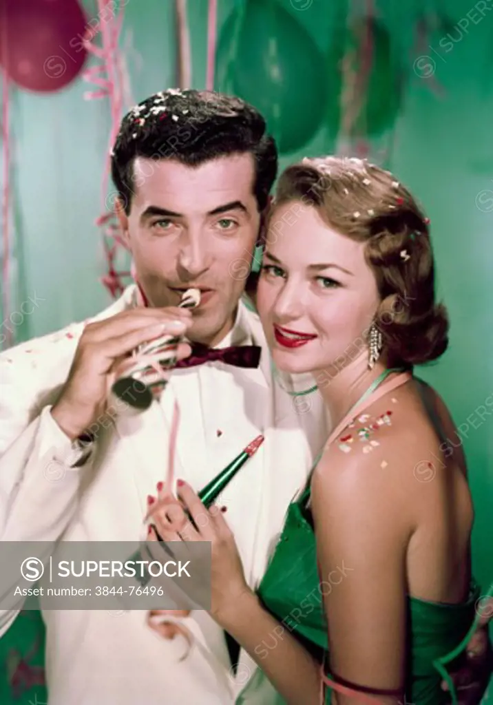 Portrait of young couple with party horn blowers