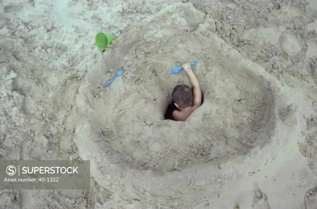 High angle view of a boy digging a hole on the beach