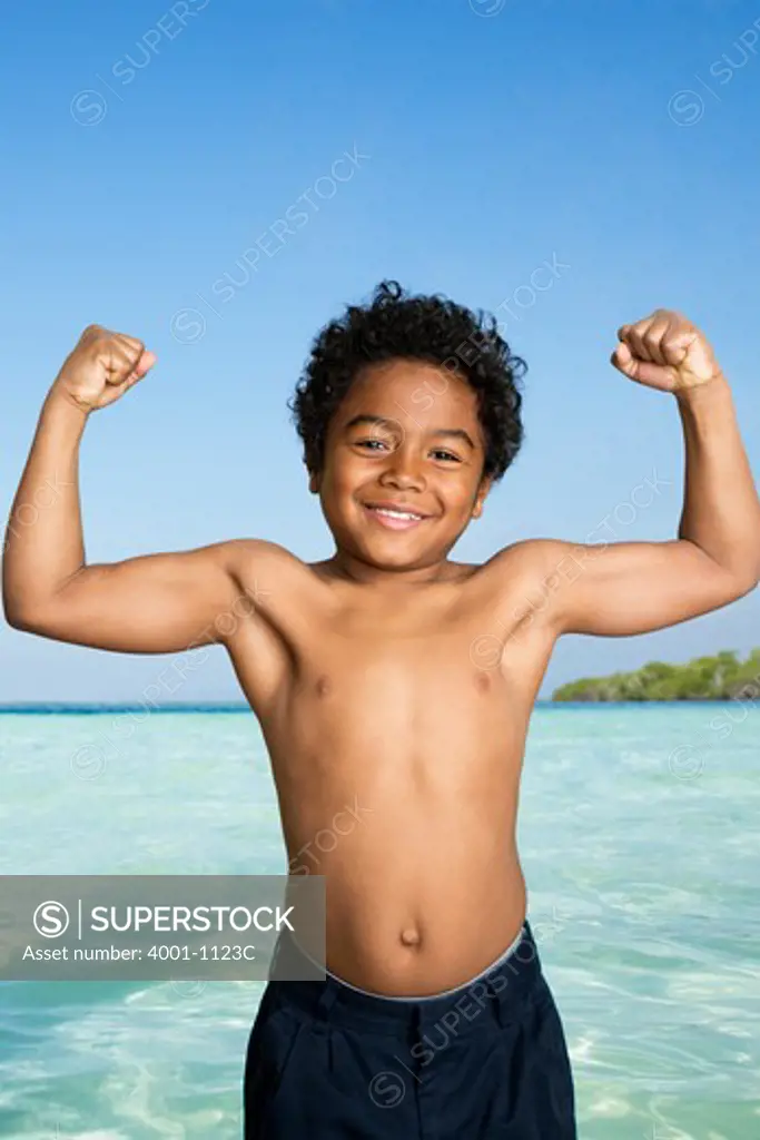 Boy flexing his muscles on the beach
