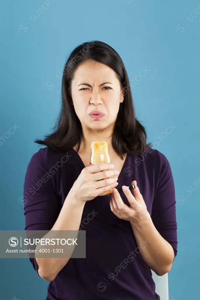 Young woman making a disgust face while looking at a bottle