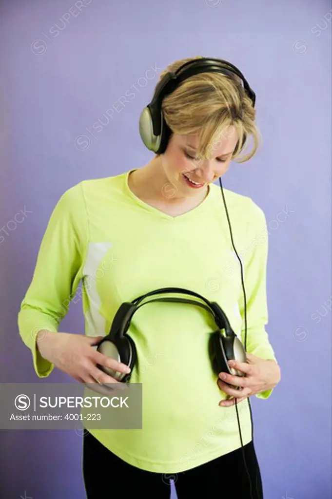 Pregnant woman pressing headphones to her belly