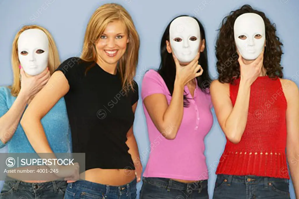 Young women standing with her friends covering their faces with masks