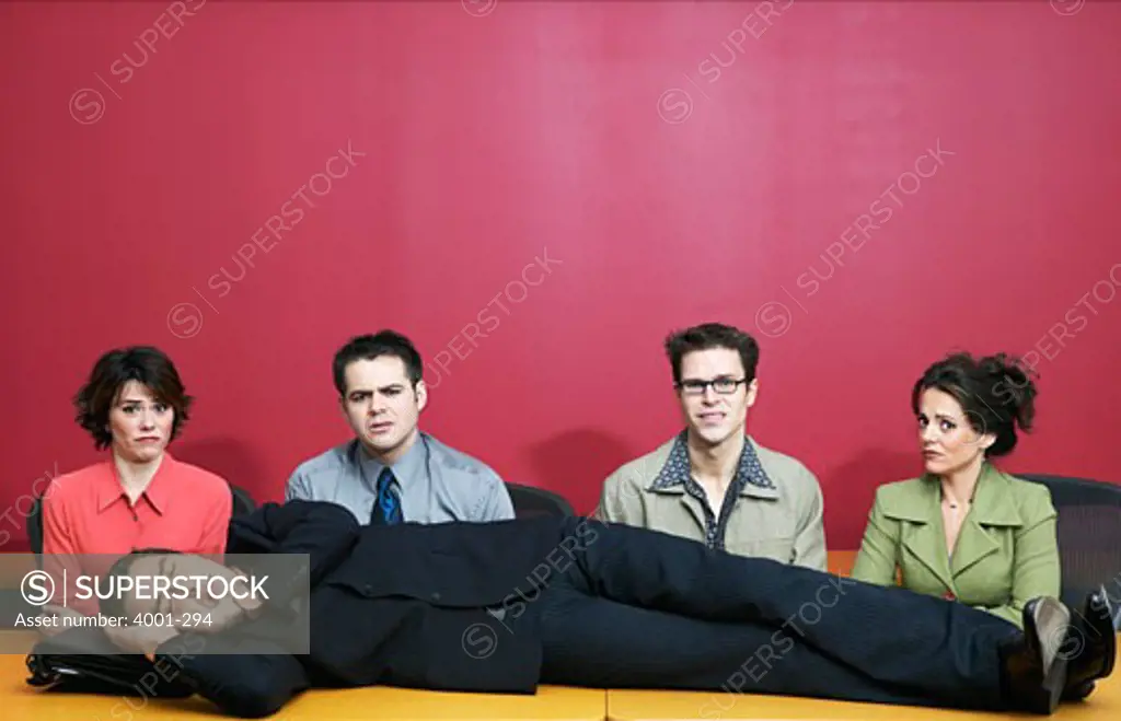 Businessman sleeping on a desk with his colleagues sitting beside him
