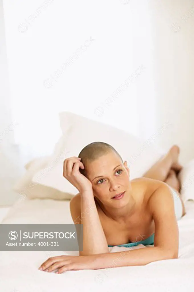 Shaved head young woman lying on the bed
