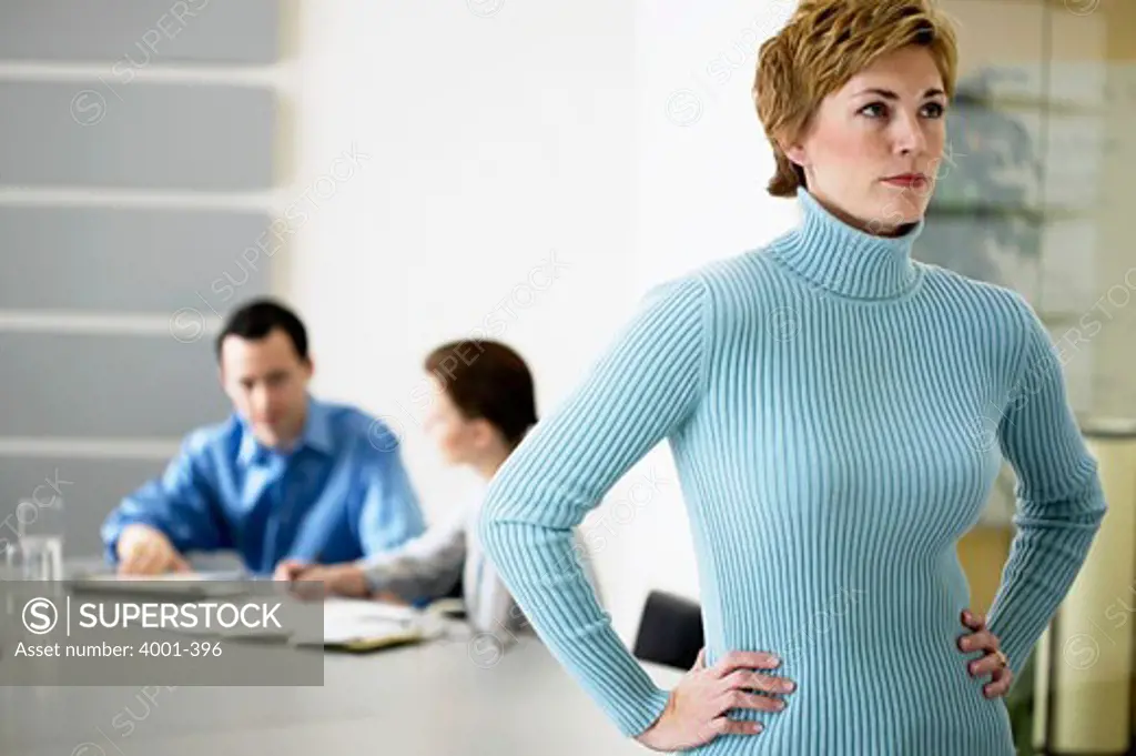 Businesswoman standing in an office with arms akimbo