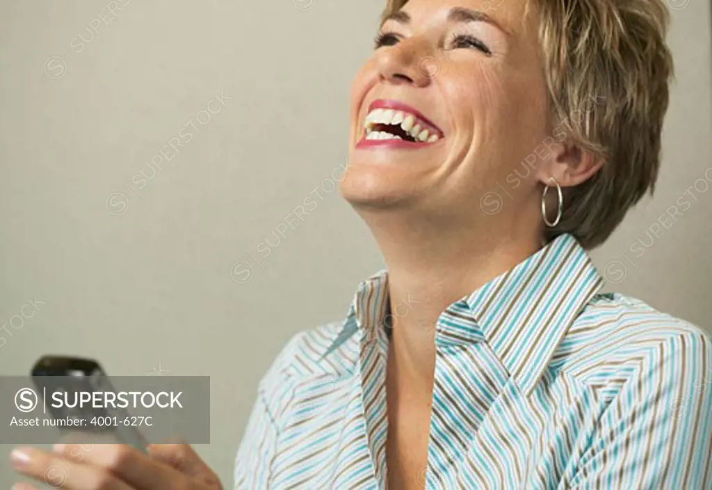 Businesswoman laughing while text messaging on a mobile phone