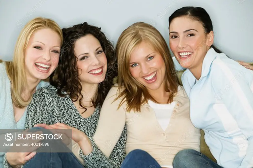 Four young women sitting together and smiling